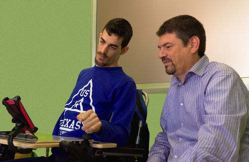 persona con parálisis cerebral usando un móbil mientras cesar observa